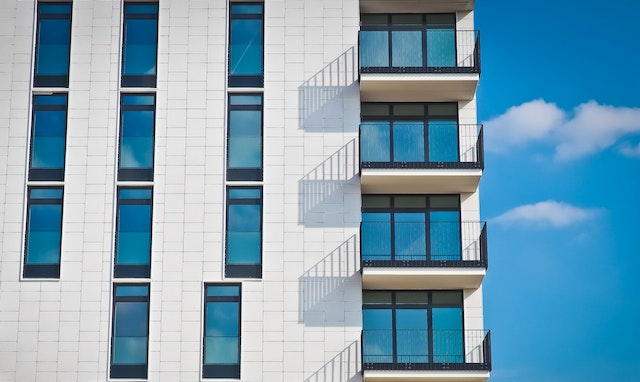 Exterior of a white apartment building with balconies in front of a blue sky